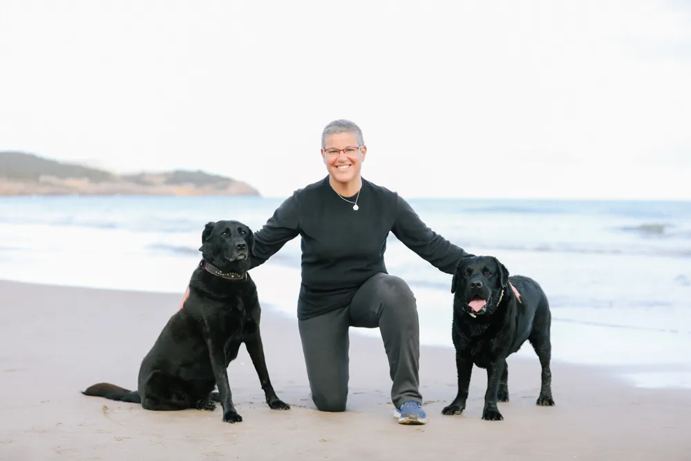 Mónica Corchado, educadora canina especializada en reactividad, en la playa con dos perros negros